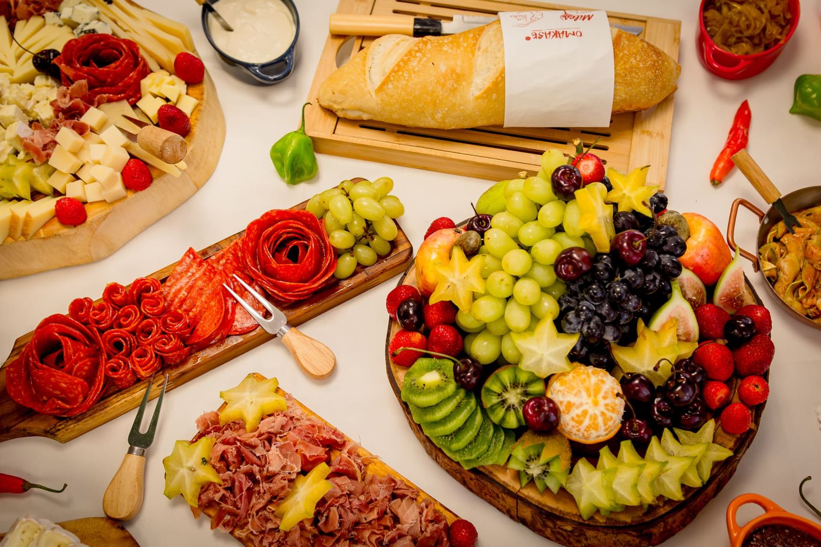 Mesa de entradas e antepastos com tâbuas de frios, queijos, frutas e pães