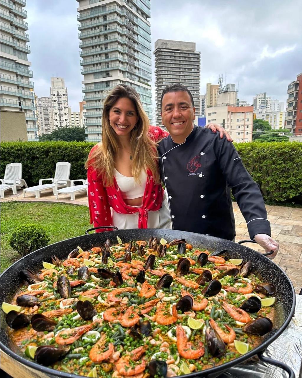 Chef Leandro Dias com cliente ao lado da paella gigante de frutos do mar no evento
