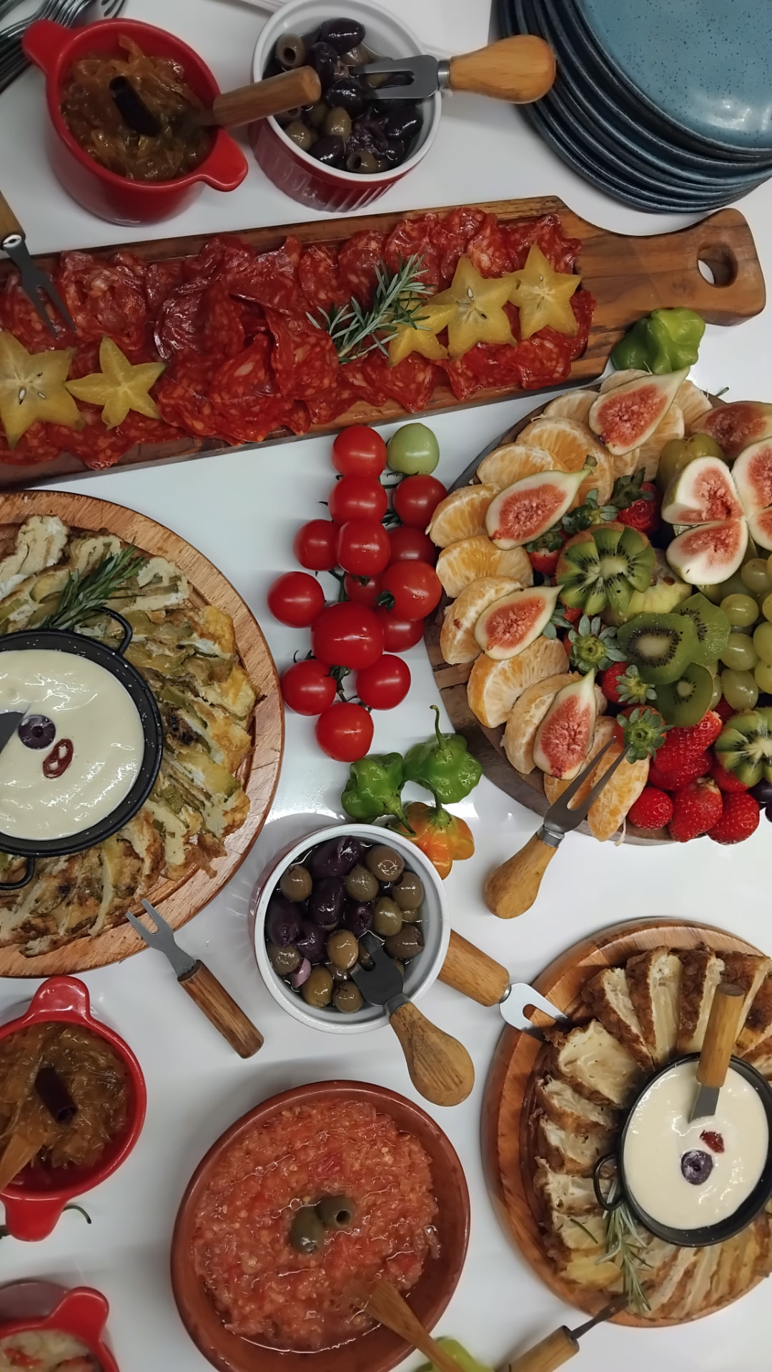 Mesa de entradas e antepastos com salada de tomates, azeitonas, pimentões e frutas
