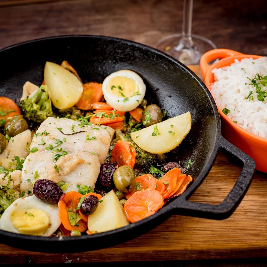 Bacalhau da casa com legumes, azeitonas, ovo e arroz na frigideira de ferro